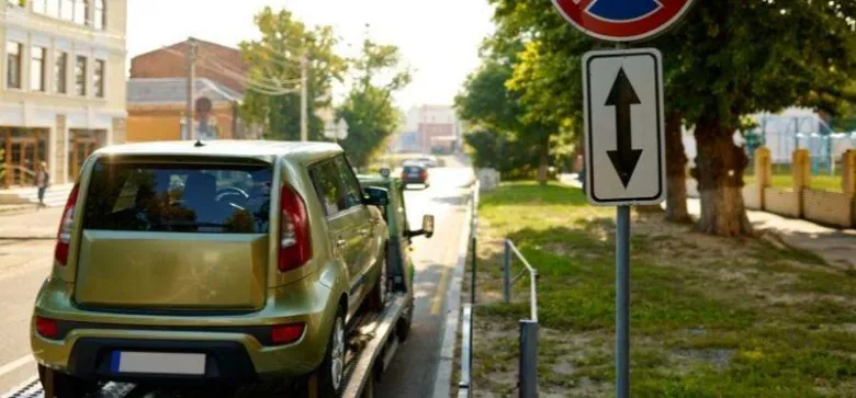 Zelené auto na nákladním vozidle u zákaznického parkování.