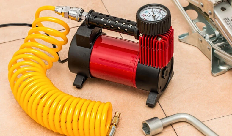 Červený kompresor vzduchu s hadicí pro nafukování pneumatik.