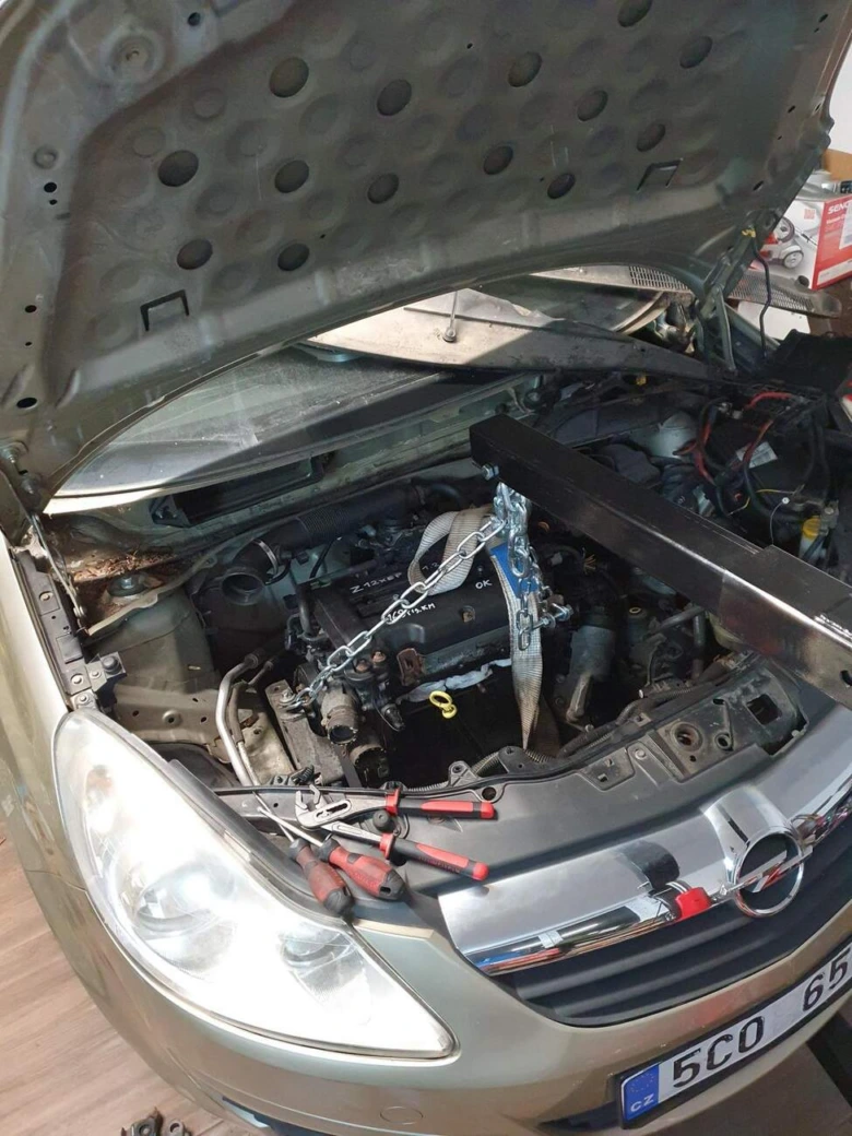 Výměna motoru v autě pomocí zdvihače s nástroji pod kapotou.