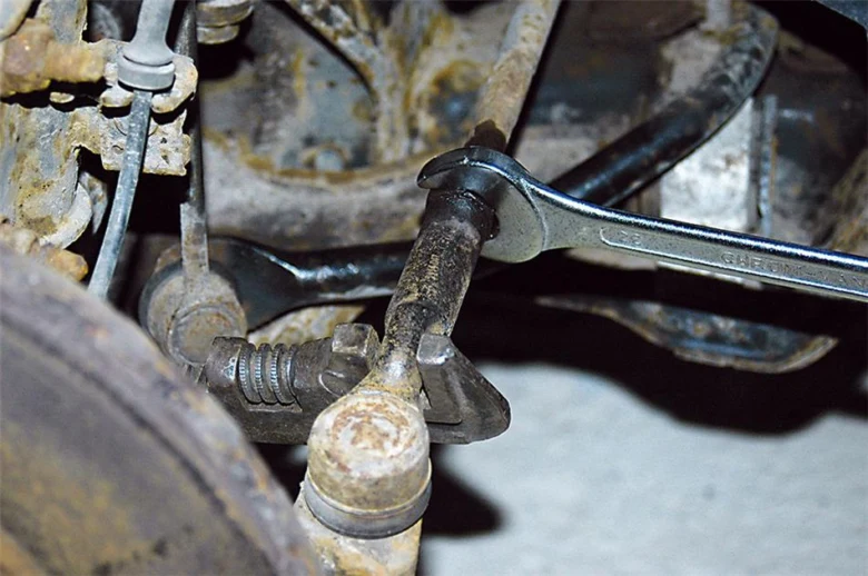 Mechanik opravuje podvozek auta klíčem kvůli hučení při jízdě.