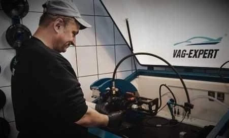 Mechanik pracuje na výměně motoru v dílně.
