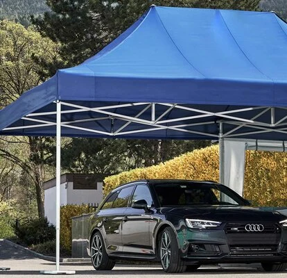 Černé auto pod modrou přenosnou garáží venku.