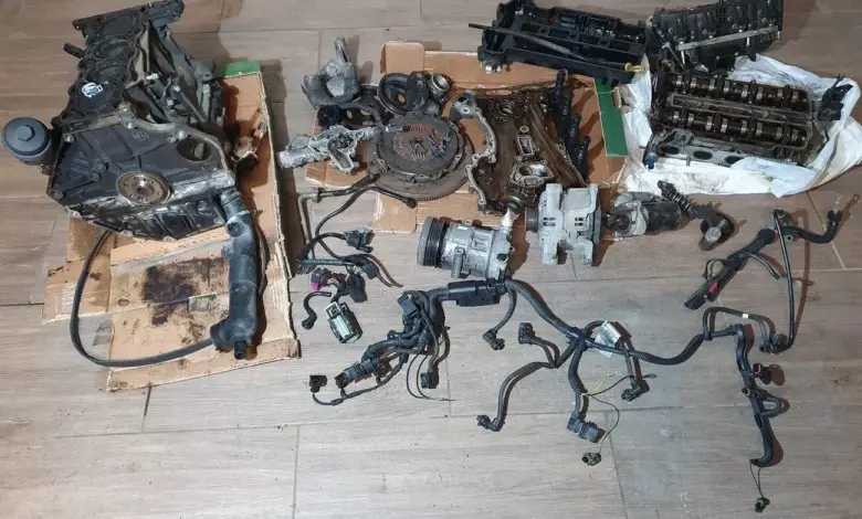 Rozložené díly motoru pro výměnu u automobilu na podlaze.