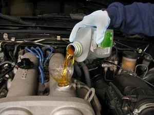 Lid nalévá motorový olej do motora automobilu.