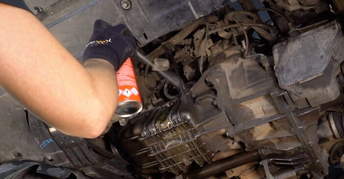 Osoba čistí motor Fordu Kuga sprejem během servisu.