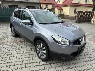 Stříbrný automobil Nissan Qashqai zaparkovaný na dlážděném dvorku.