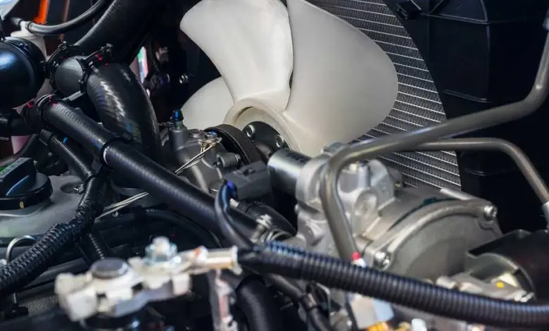 Bílý ventilátor chladiče motoru v autě s radiátorem.