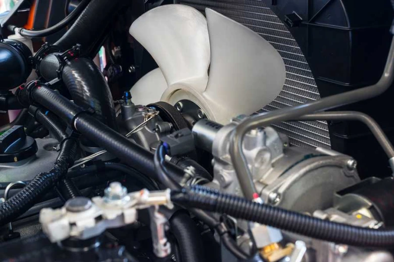 Bílý ventilátor chladiče motoru v autě s radiátorem.