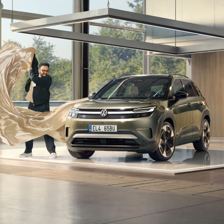 Muž odhaluje nový elektrický VW ID.4 na výstavě v salonu.