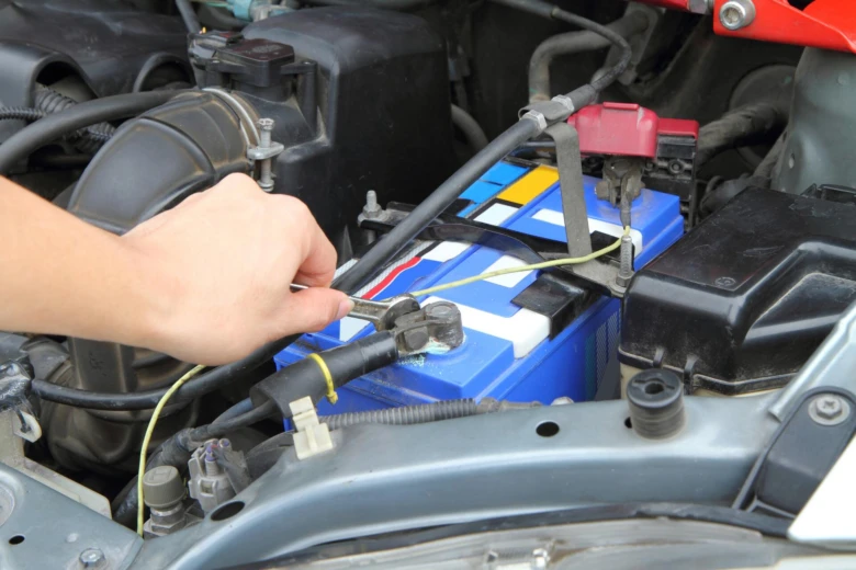 Ruční připojení kabelu k pozitivnímu pólu automobilové baterie.
