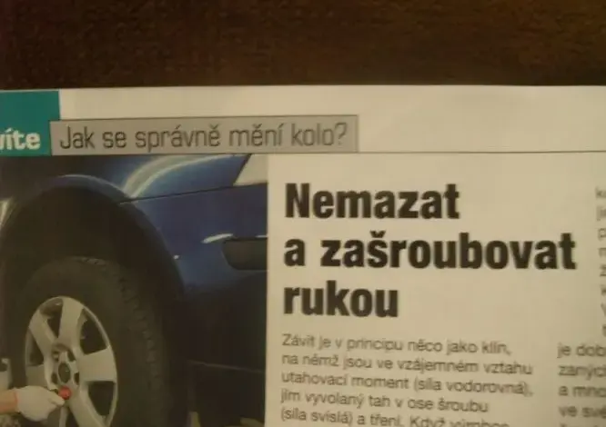 Člověk ručně utahuje šrouby kola modrého auta.