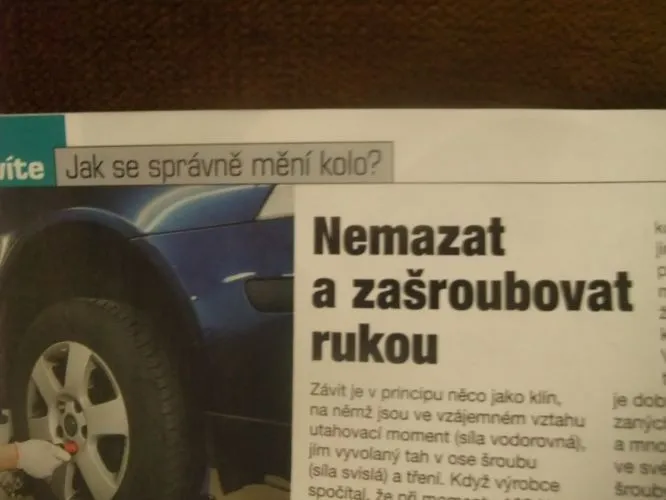 Člověk ručně utahuje šrouby kola modrého auta.