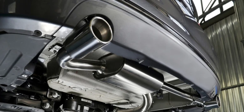 Detailní pohled na výfukový systém automobilu pod karoserií.