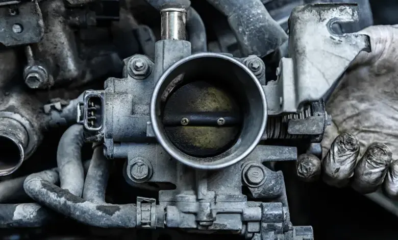 Zblízka viditelná znečištěná škrticí klapka v motoru automobilu.