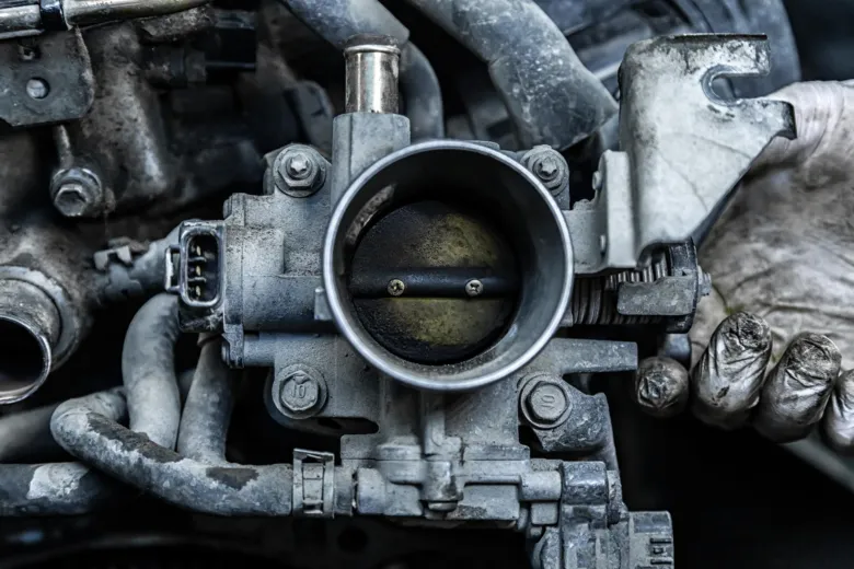 Zblízka viditelná znečištěná škrticí klapka v motoru automobilu.