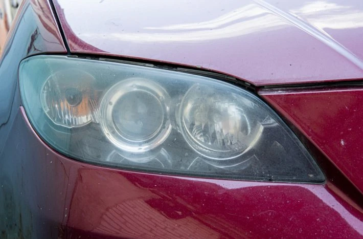 Zamlžený světlomet uvnitř červeného automobilu.