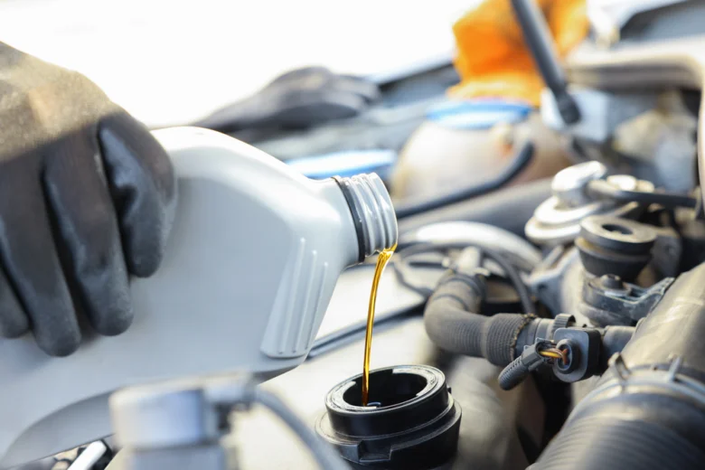 Zlatý olej se nalévá do otvoru pro výměnu oleje v automobilovém motoru.