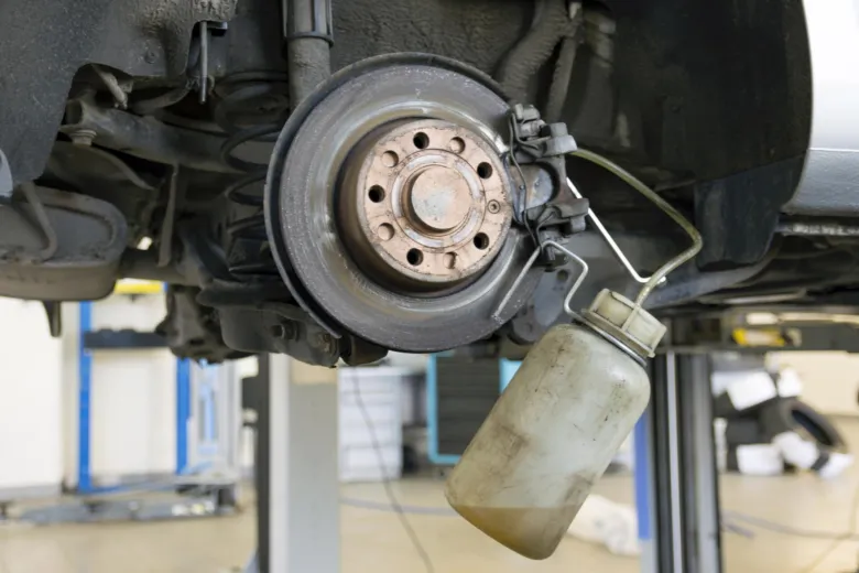 Odvádění staré brzdové kapaliny z automobilu během údržby.