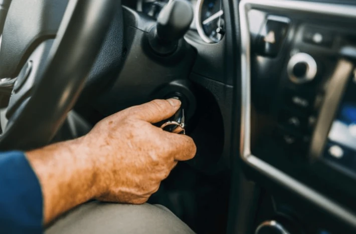 Ruka otáčí klíč v zapalování automobilu.