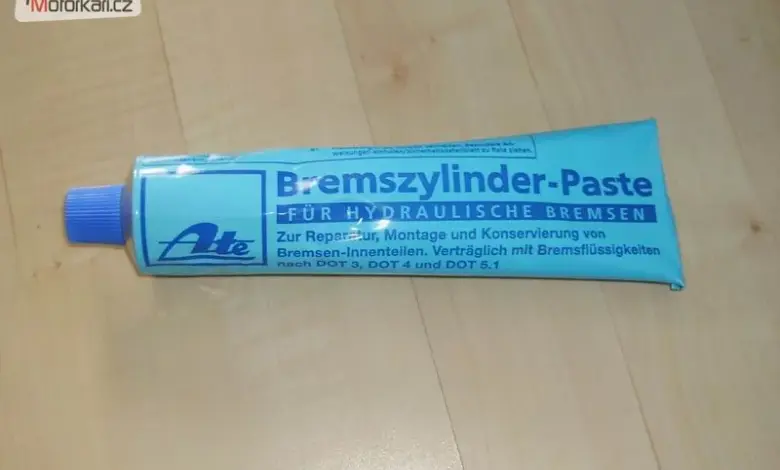 Tubka s pastou pro mazání brzdových válců na dřevěném povrchu.