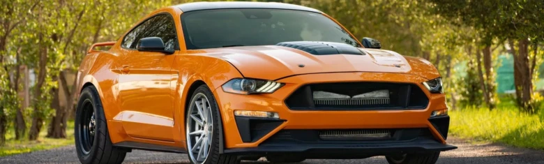 Oranžový sportovní automobil zaparkovaný na štěrkové cestě.