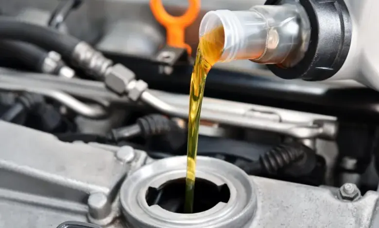 Zlatý motorový olej se nalévá do otvoru pro doplnění oleje v automobilovém motoru.