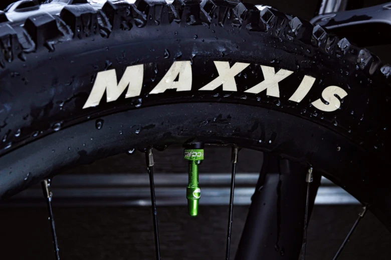 Zelený ventil Presta na kole s pneumatikou značky Maxxis.