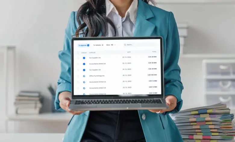 Žena drží notebook s seznamem faktur pro schválení.