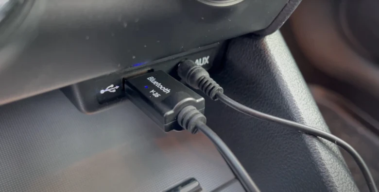Bluetooth adaptér zapojený do AUX vstupu v autě.