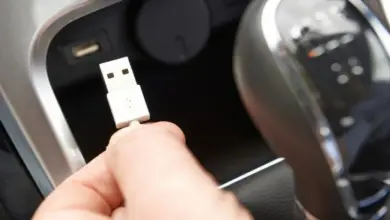 Ruka drží bílý USB konektor uvnitř vozu při připojení k portu.