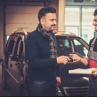 Muži předávají klíče auta v servisu s papíry.