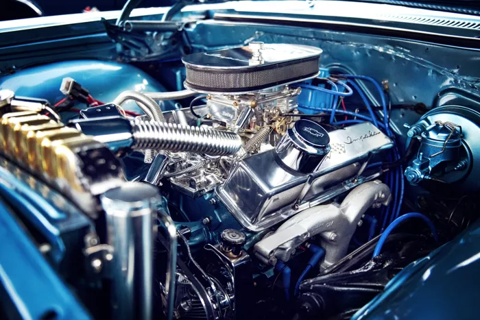 Detailní pohled na lesklý benzinový motor v otevřeném kapotě vozu.