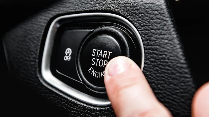 Prst tlačí na spínač Start Stop Engine v autě.