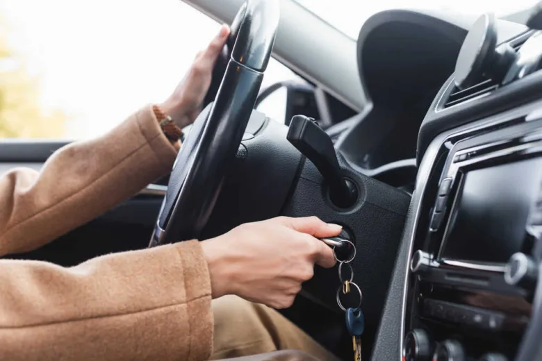 Osoba zapíná auto klíčem do zámku při startování.