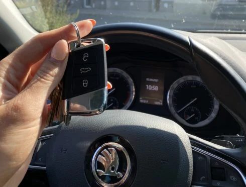 Ruka drží klíč od auta u volantu Škody.