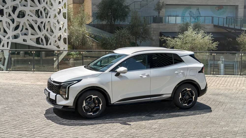 Bílý SUV Kia Sportage páté generace na asfaltu.