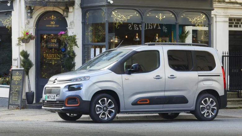 Stříbrný Citroën Berlingo zaparkovaný před obchodem s výzdobou.