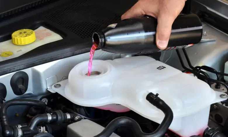 Nalévání růžové chladicí kapaliny do rozšiřovací nádrže pod kapotou.