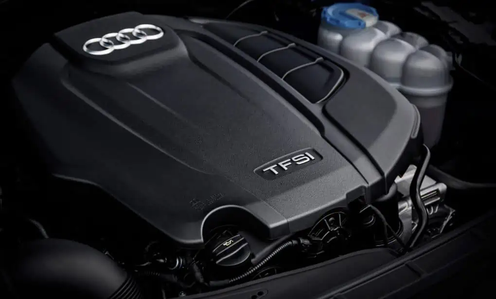 Motor Audi s logem na krytu v podkapotí vozu.