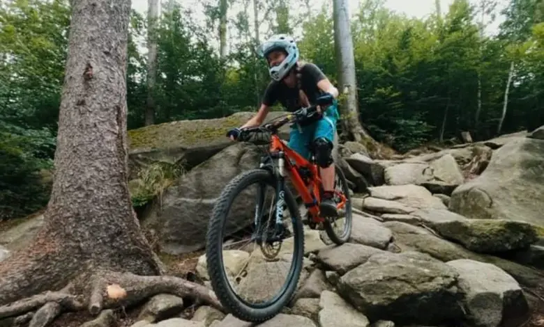 Cyklista na horské kolo jezdí po kamenité cestě v lese.