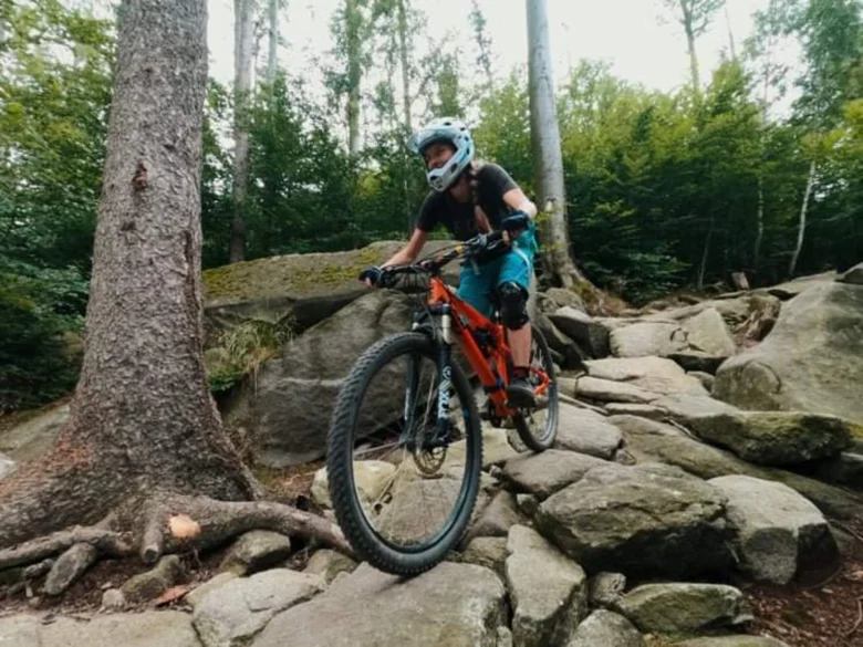 Cyklista na horské kolo jezdí po kamenité cestě v lese.