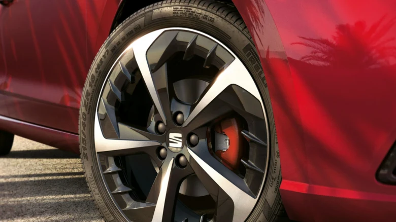 Detail červeného automobilu s narážkou na pneumatiku.