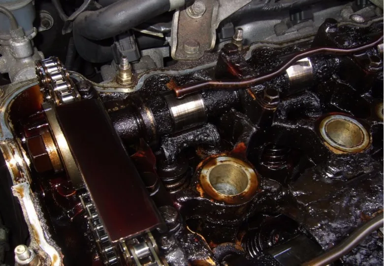 Otevřený motor s viditelným olejem a benzínovými stopami.