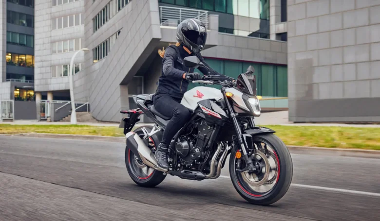 Osoba na motocyklu Hondy CB300F jezdí po městské ulici.