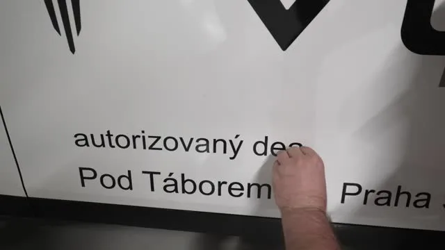 Ruka odstraňuje nalepku z bílého povrchu.
