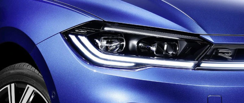 Blízký záběr na přední světlomět modrého Volkswagenu Polu.