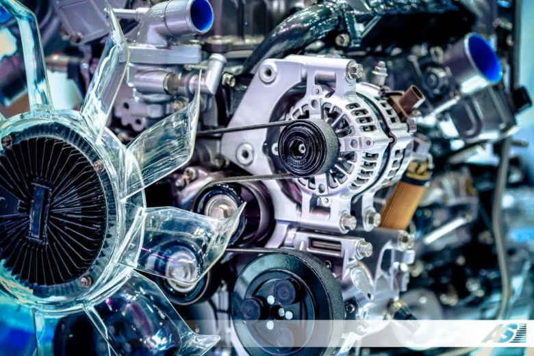 Detailní pohled na automobilový motor s alternátorem a řemeny.