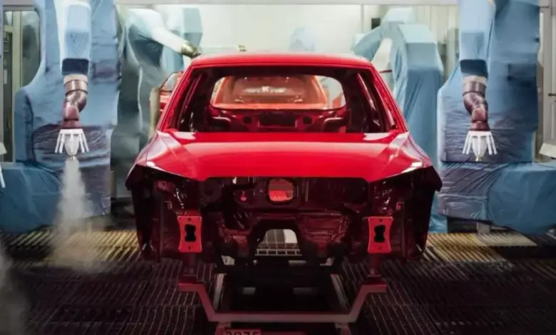 Robotic paří barví červené auto v lakovně