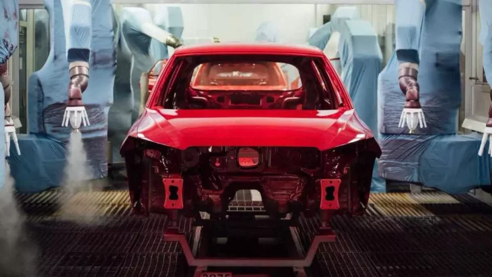 Robotic paří barví červené auto v lakovně