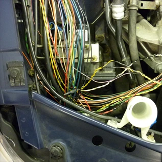 Přehled automobilové kabeláže s mnoha barevnými vodiči v motorovém prostoru.